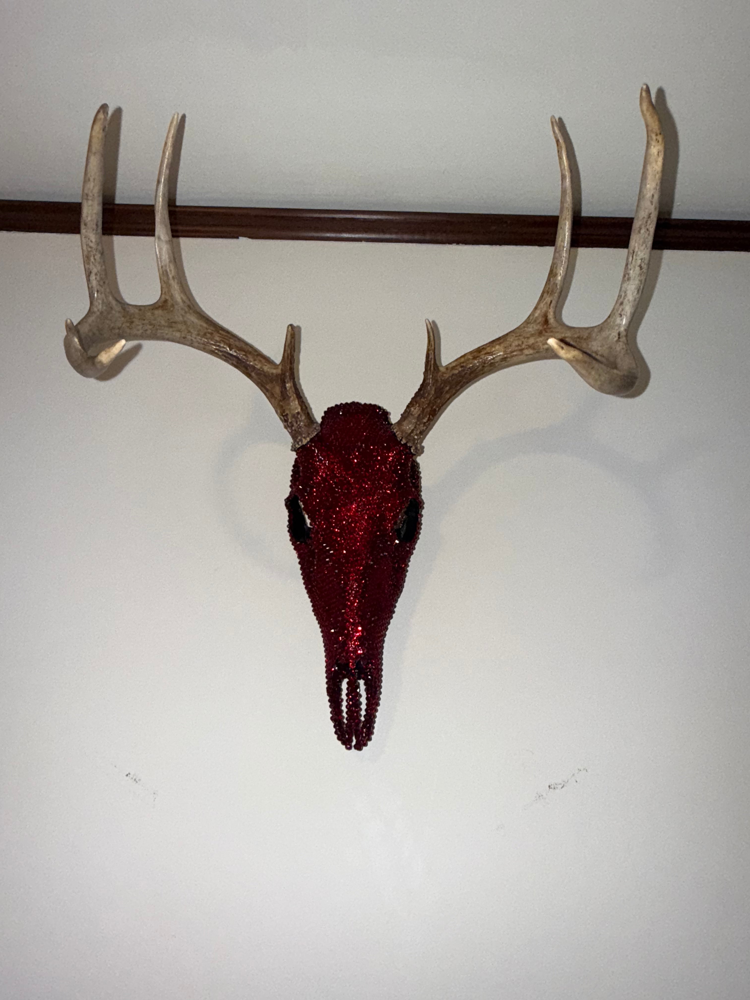 Crimson Autumn crystallized deer skull sculpture shown full on a wall, red rhinestones over a black base